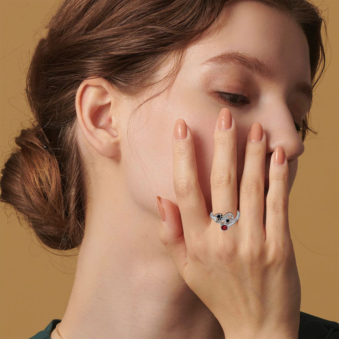 Justerbart ring med sorte poteaftryk og rødt ædelsten