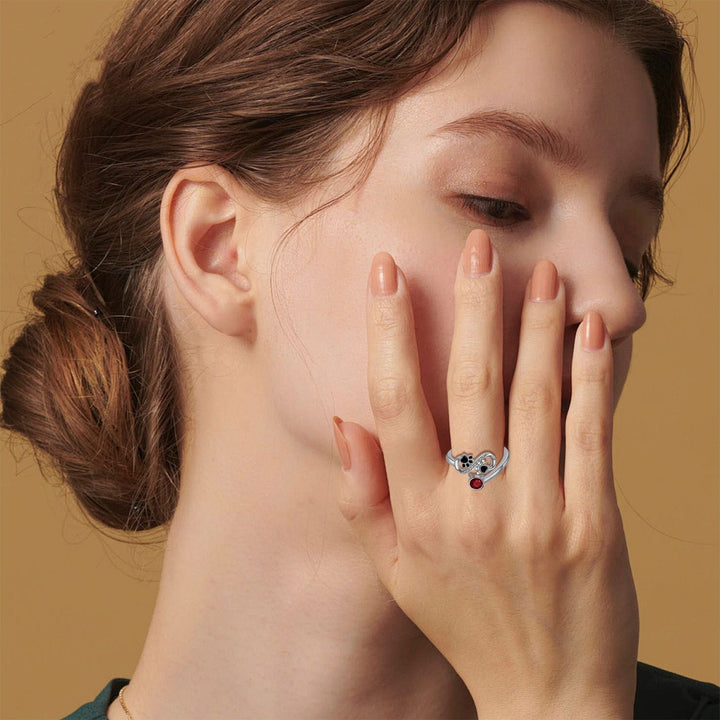 Justerbart ring med sorte poteaftryk og rødt ædelsten